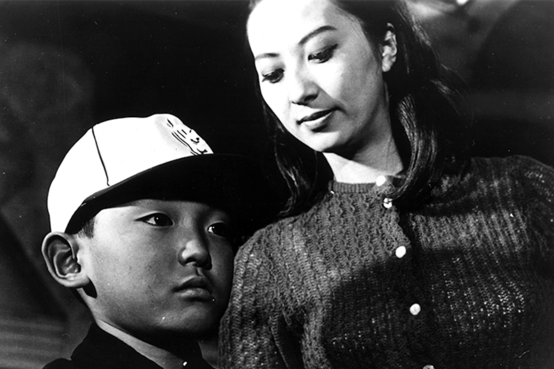 Close-up of the Boy in a baseball cap with his stepmother, played by Akiko Koyama, looking down at him in Boy (1969)
