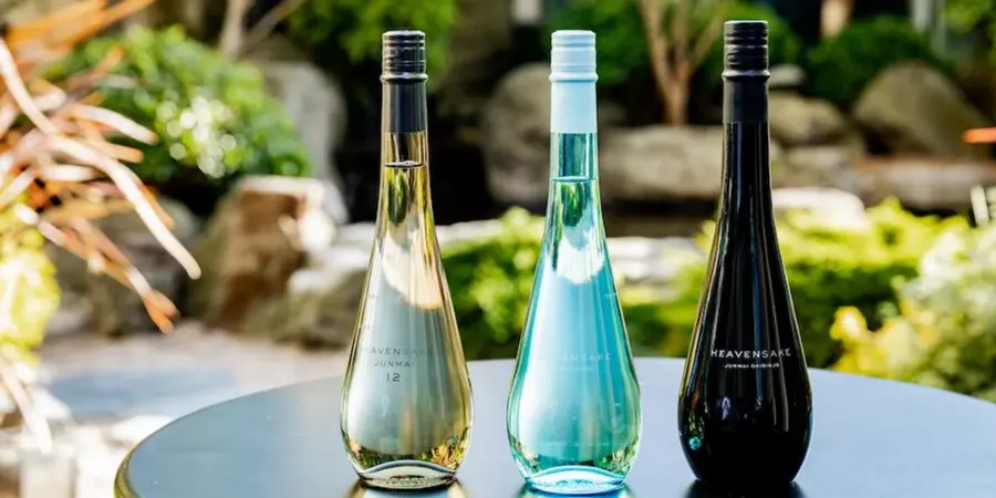 Three HeavenSake Japanese sake bottles in white, turquoise, and black displayed outdoors