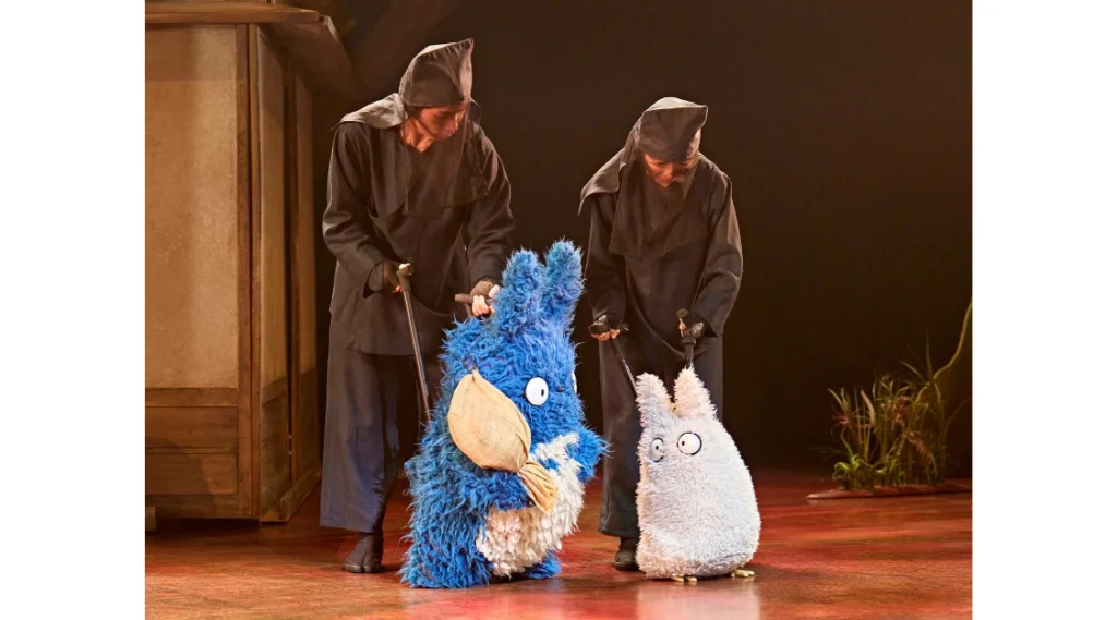 Members of the puppetry ensemble operate blue and white forest spirit puppets on stage in My Neighbour Totoro at the Gillian Lynne Theatre.