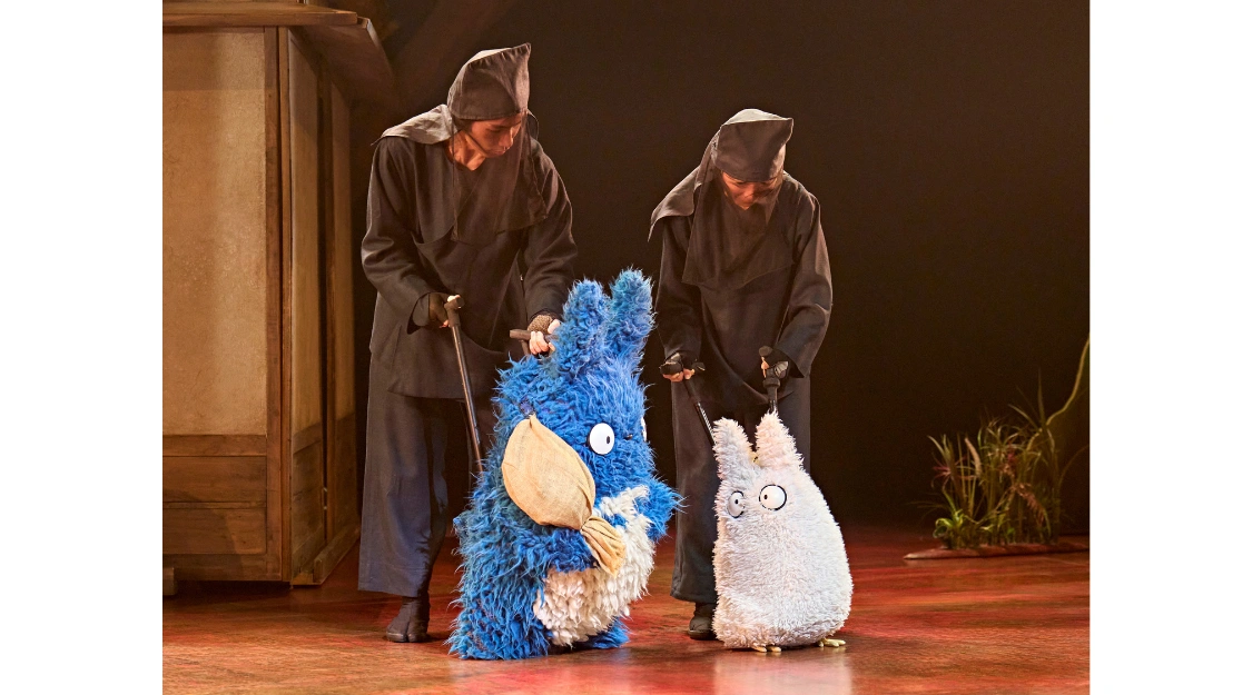 Members of the puppetry ensemble operate blue and white forest spirit puppets on stage in My Neighbour Totoro at the Gillian Lynne Theatre.