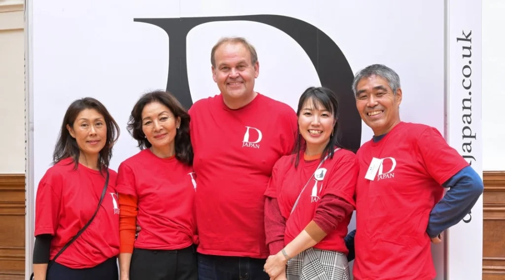 Five members of the Drink Japan team wearing red event T-shirts pose together in front of the Drink Japan branding.