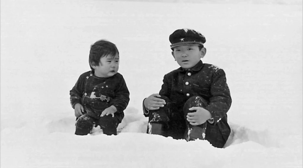 The Boy and his younger brother sitting side by side in deep snow in the Otaru sequence of Nagisa Ōshima's Boy (1969)