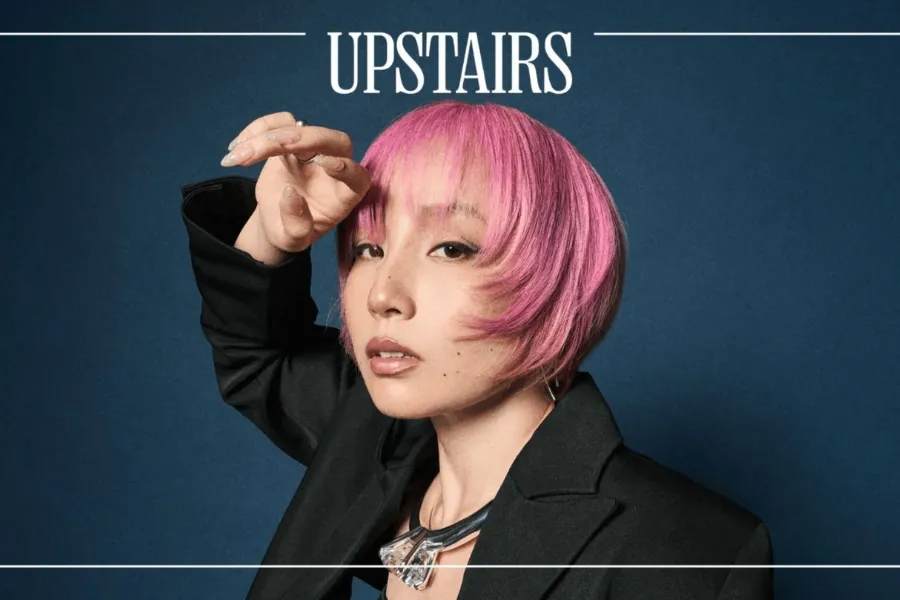 Nao Yoshioka wearing a black blazer and statement necklace in a promotional portrait for Upstairs at Ronnie Scott’s