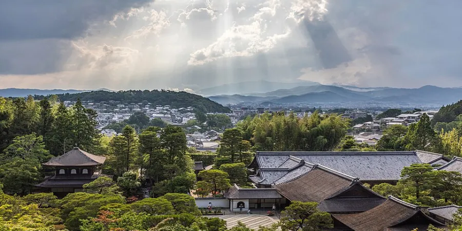 Panoramic view of modern Kyoto with traditional temple rooftops, residential districts and mountains beyond