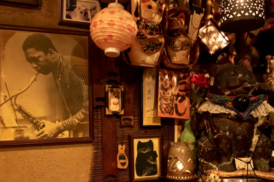 Eclectic interior of Peter Cat jazz bar in Tokyo featuring Japanese cat figurines, lanterns, artwork, vintage decor and a historic jazz musician photograph ©Photo by Philip Arneill from his book Tokyo Jazz Joints