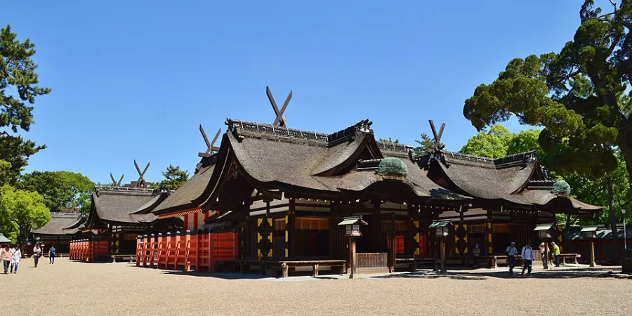 Main shrine buildings at Sumiyoshi Taisha in Osaka, Japan, featuring traditional Japanese architecture, curved thatched roofs, red wooden structures and surrounding trees.