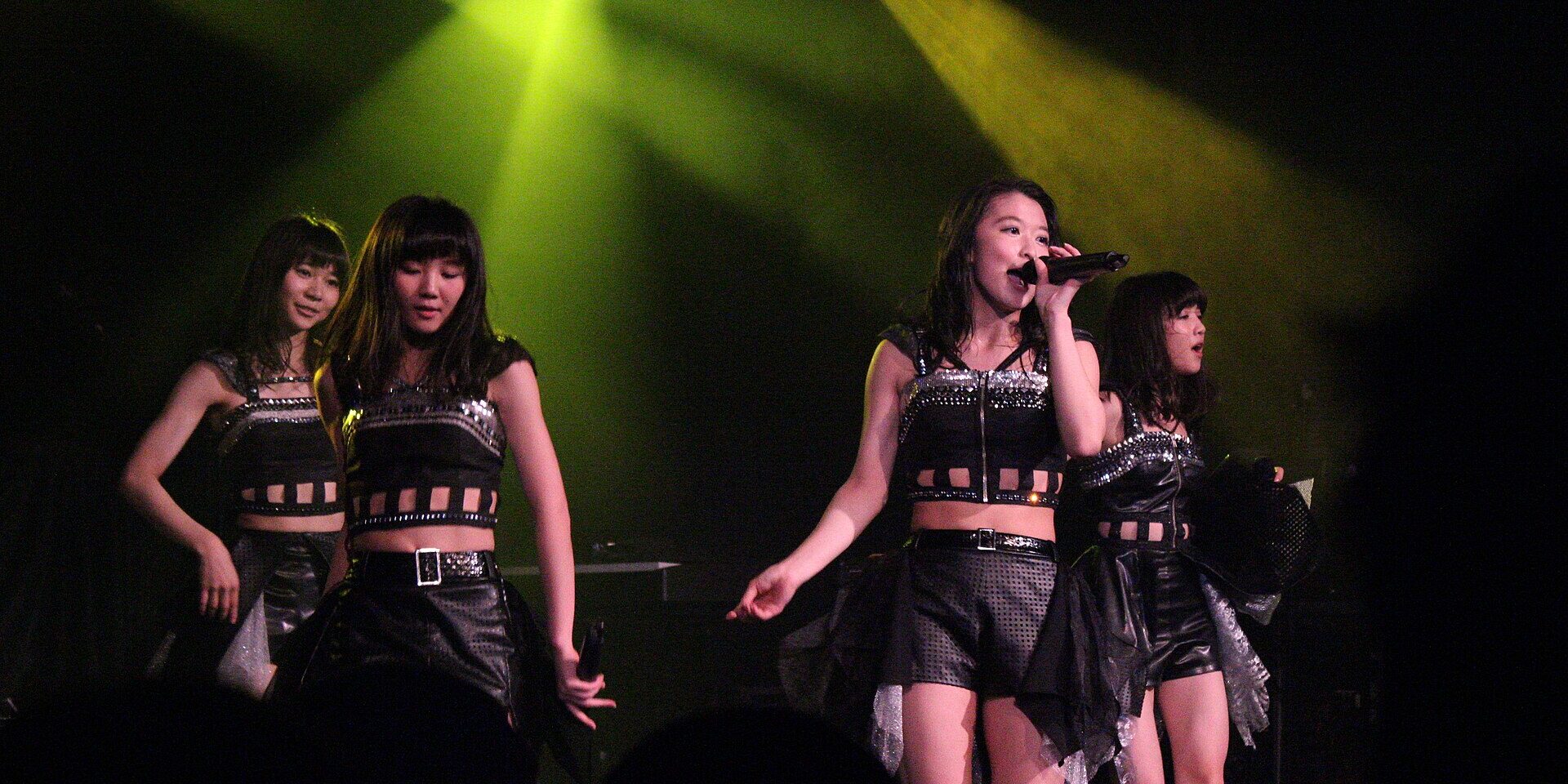 Japanese idol group Tokyo Girls Style performing on stage under green lights at Hyper Japan in London