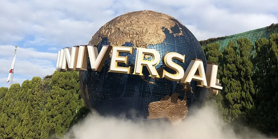 Universal Studios Japan globe entrance in Osaka, Japan, surrounded by trees and mist under a blue sky
