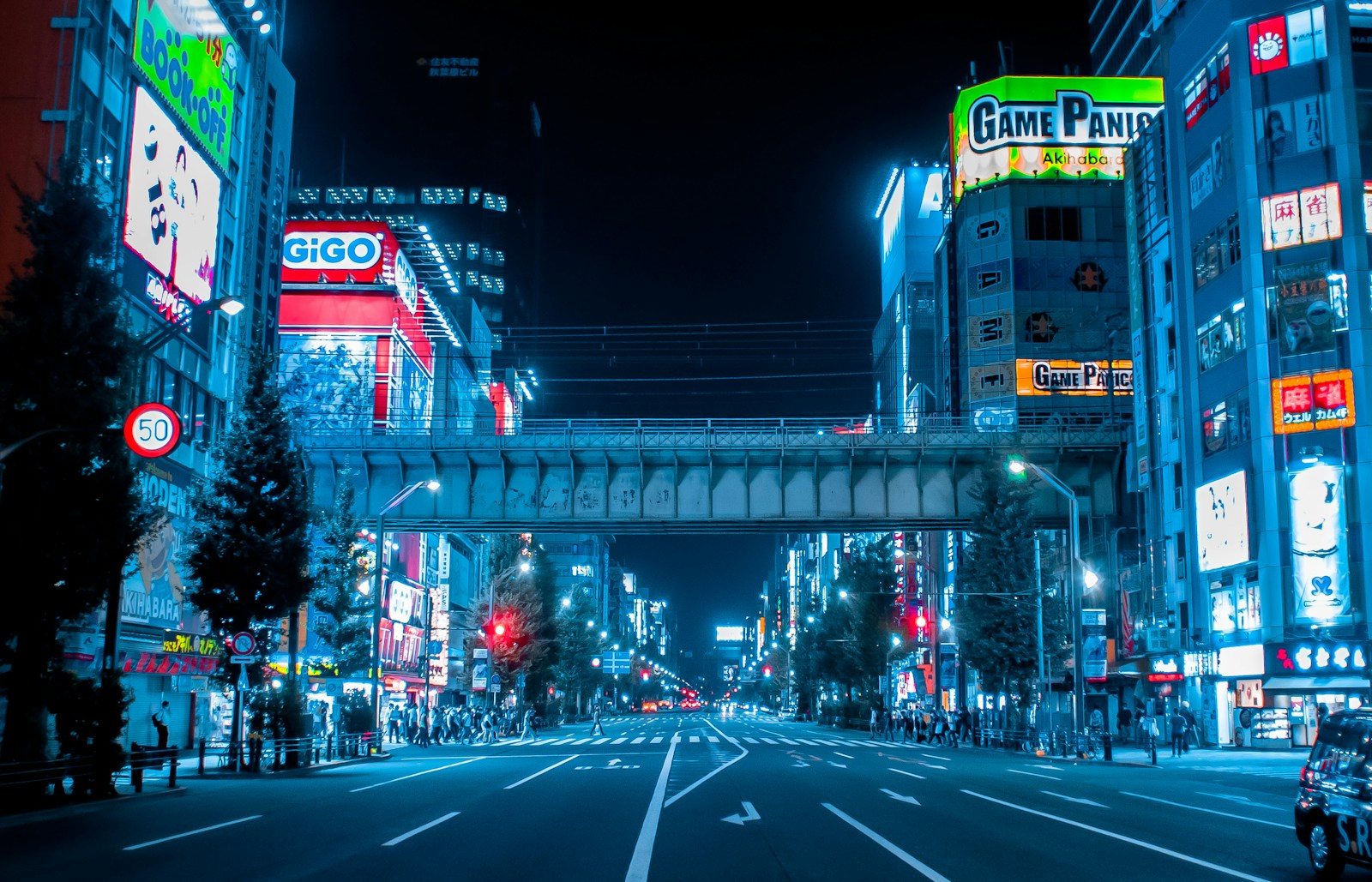 Empty main street in Akihabara, Tokyo, at night lined with illuminated arcade and shop signs
