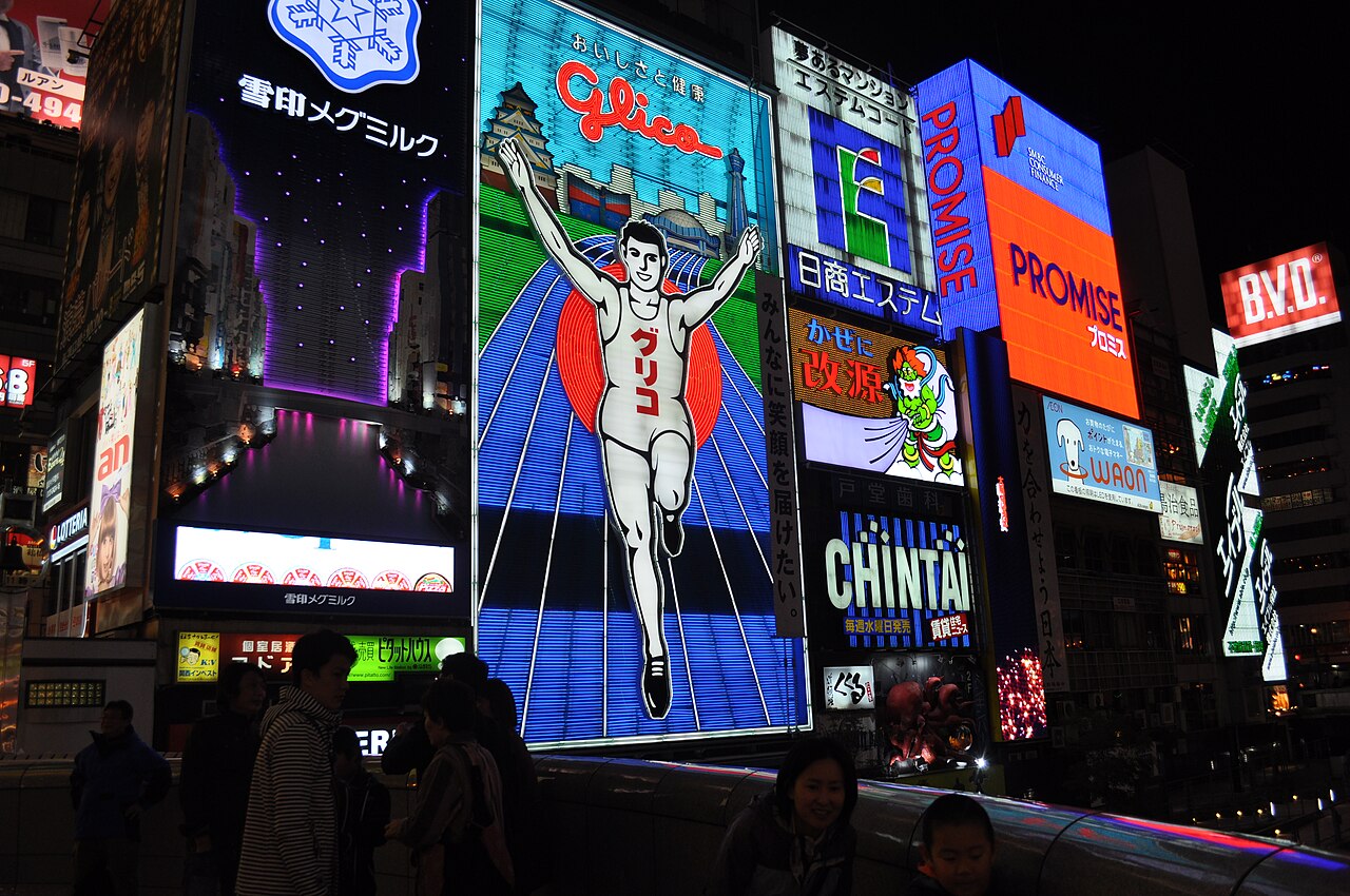 The Glico running man sign and other neon billboards lit up at night in Dotonbori, Osaka