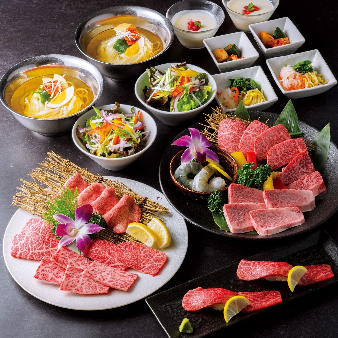 A yakiniku spread of raw wagyu cuts, cold noodles, salads and small side dishes at Gyubei Souan