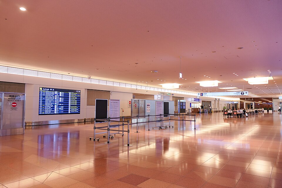 Arrival lobby of Haneda Airport Terminal 3 with a flight information screen on the wall