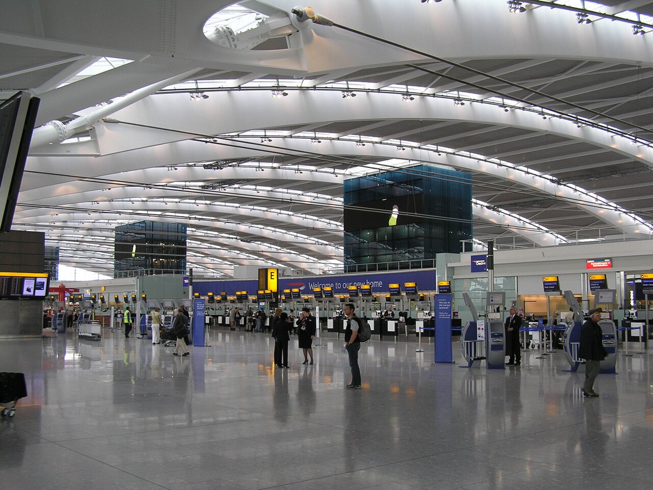 The departures hall at Heathrow Terminal 5, with its curved white roof, check-in desks and travellers