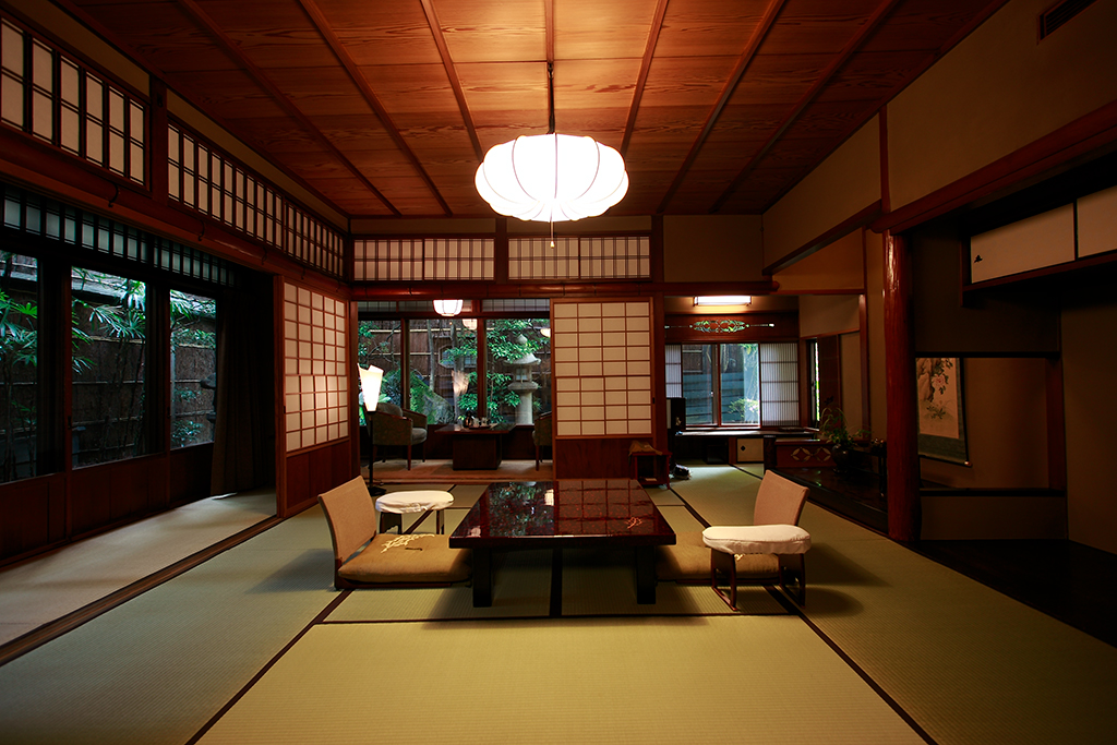 Tatami guest room at Hiiragiya in Kyoto with low table, floor chairs and paper screens opening onto a garden
