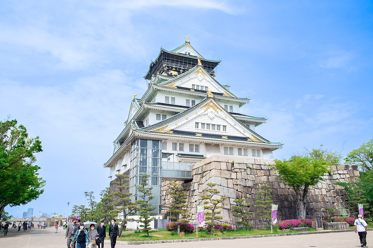 Osaka Castle main tower rising above its stone base under a blue sky