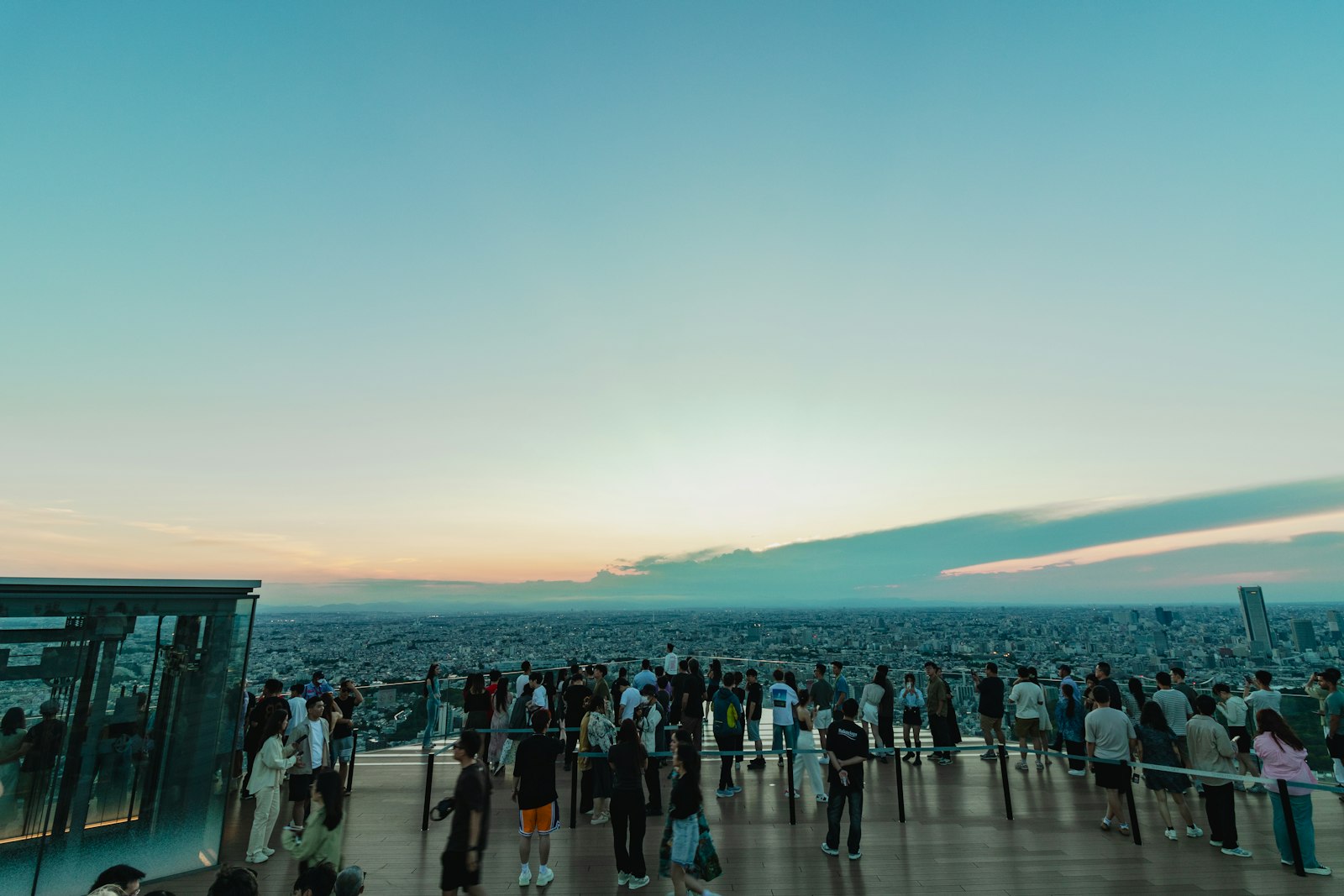 Visitors on the Shibuya Sky rooftop deck at dusk with the Tokyo skyline behind