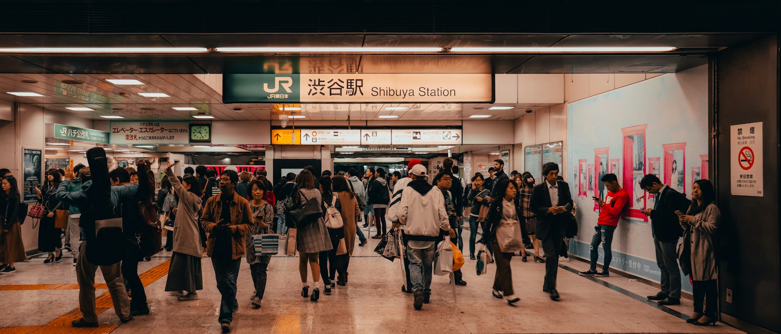 Crowds of people walking through the JR concourse inside Shibuya Station, Tokyo