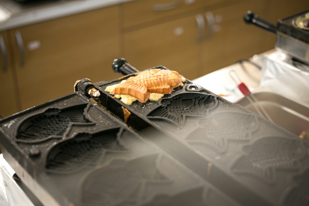 A freshly cooked taiyaki resting on an open fish-shaped taiyaki mould