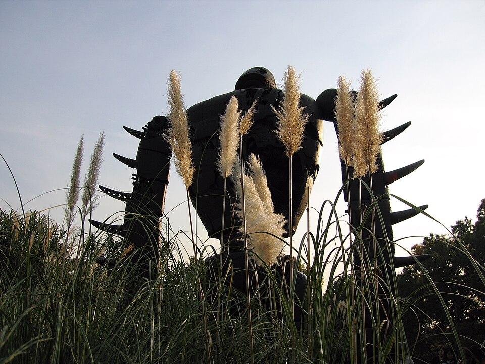 The robot soldier from Castle in the Sky standing among tall grasses on the rooftop garden of the Ghibli Museum in Mitaka
