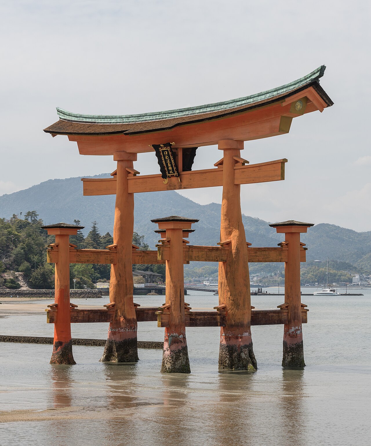 The vermilion floating torii gate of Itsukushima Shrine standing in shallow water at low tide off Miyajima