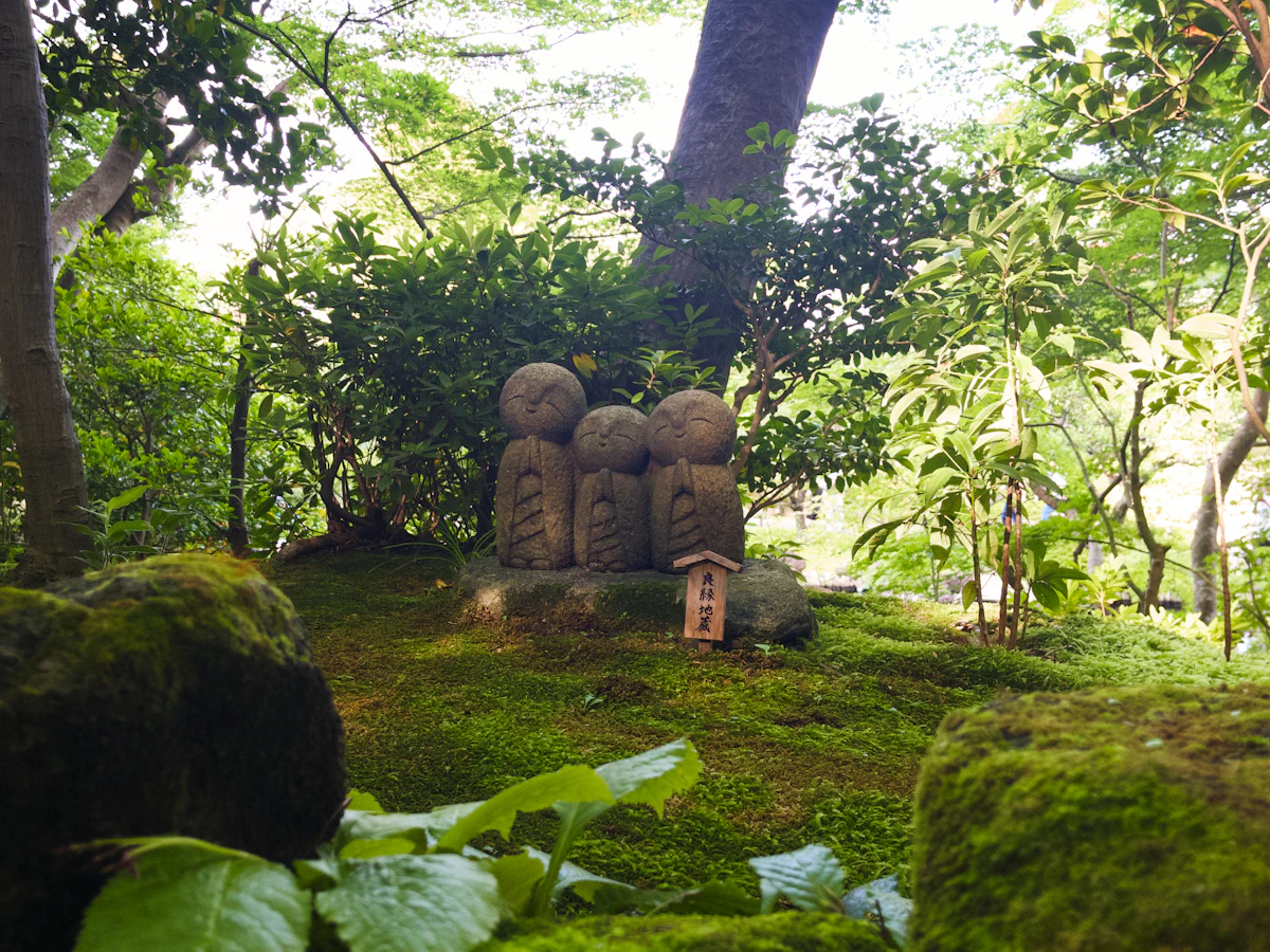 Small stone Jizō statues on a mossy bank in the garden at Hasedera temple, Kamakura
