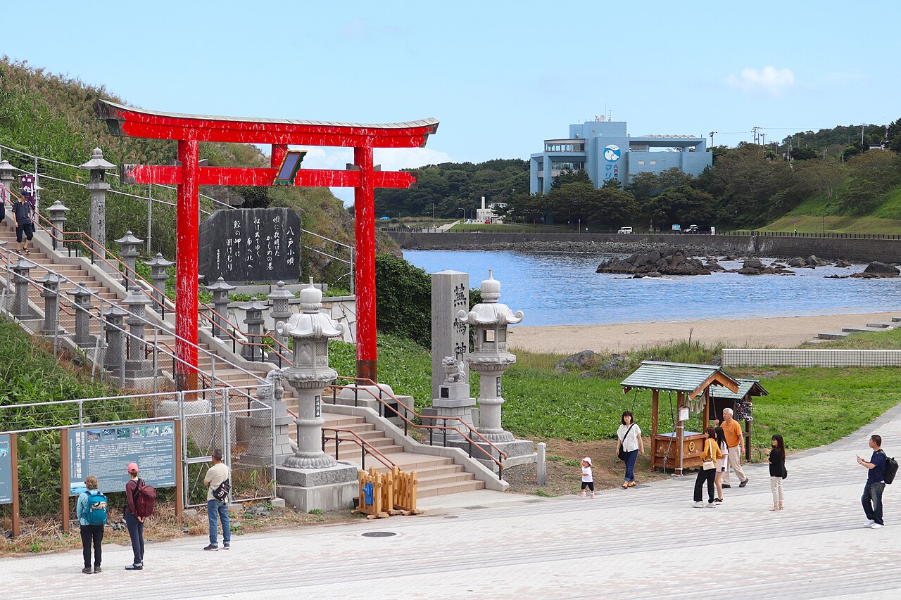 A red torii gate and stone steps leading up to Kabushima Shrine on the Hachinohe coast in Aomori Prefecture