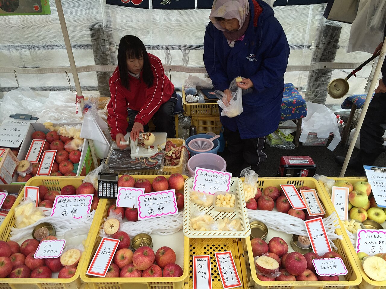 A stallholder at the Miyagawa Morning Market in Takayama selling Hida apples and sliced apple samples