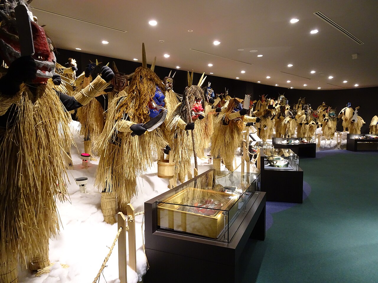 Rows of Namahage costumes with straw capes and demon masks on display