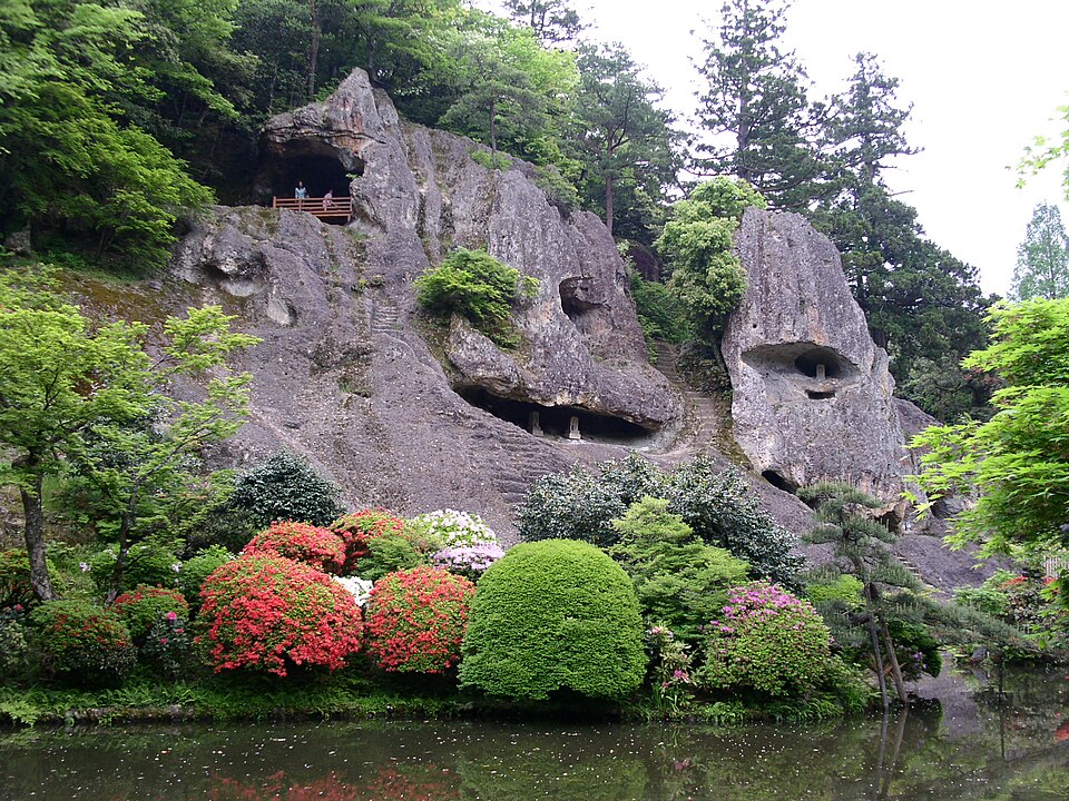 The weathered rock cliffs of the Kiseki Yusenkyo garden at Natadera, with azaleas and a pond below
