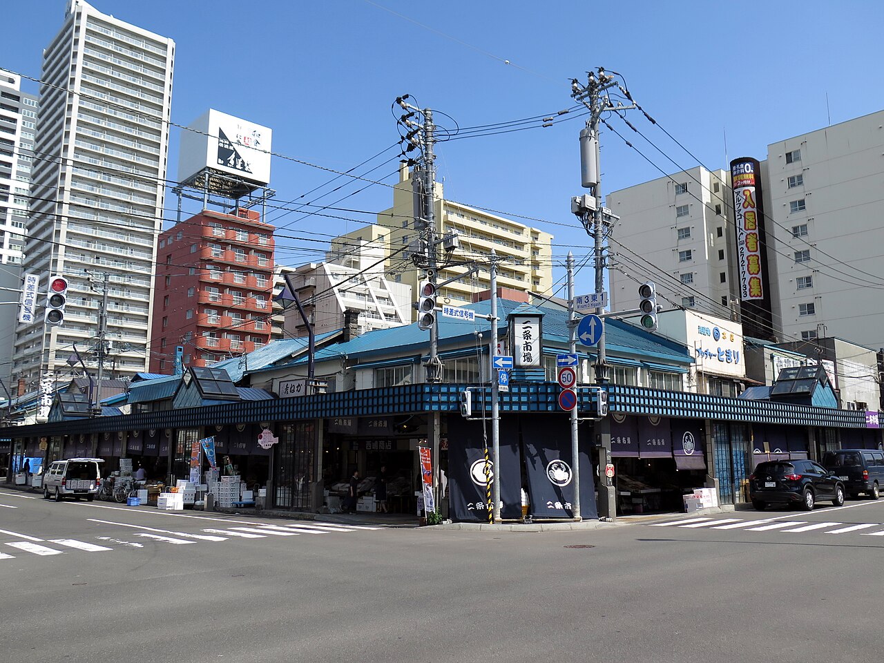 Low rise seafood shops of Nijo Market on a street corner in central Sapporo, Hokkaido, with tower blocks behind