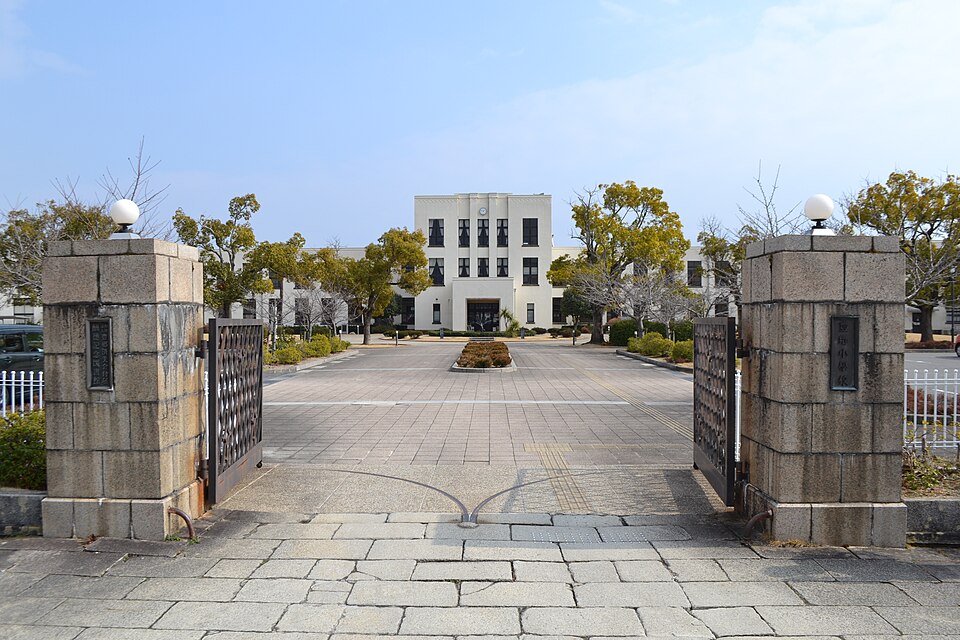 The white 1937 main building of the old Toyosato Elementary School seen through its stone gateposts
