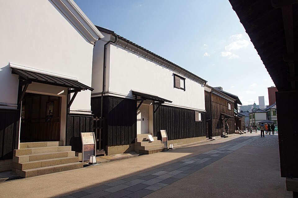 Row of restored white walled warehouses with black wooden lower walls along the main street of Dejima in Nagasaki