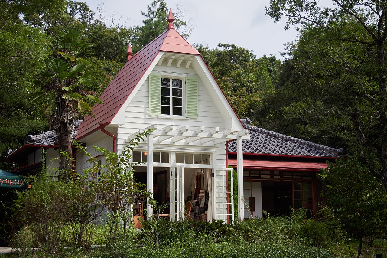 Satsuki and Mei’s House from My Neighbour Totoro, a white wooden house with a red roof and a Japanese style wing, among trees in Dondoko Forest