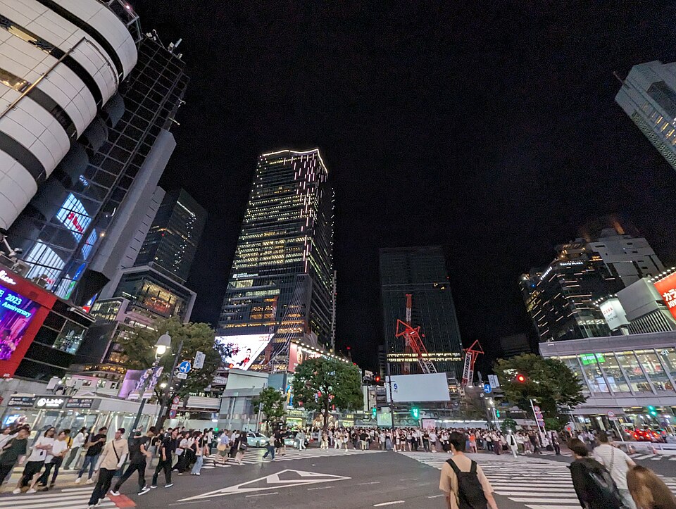 Crowds crossing Shibuya Scramble Crossing at night under lit-up towers and screens