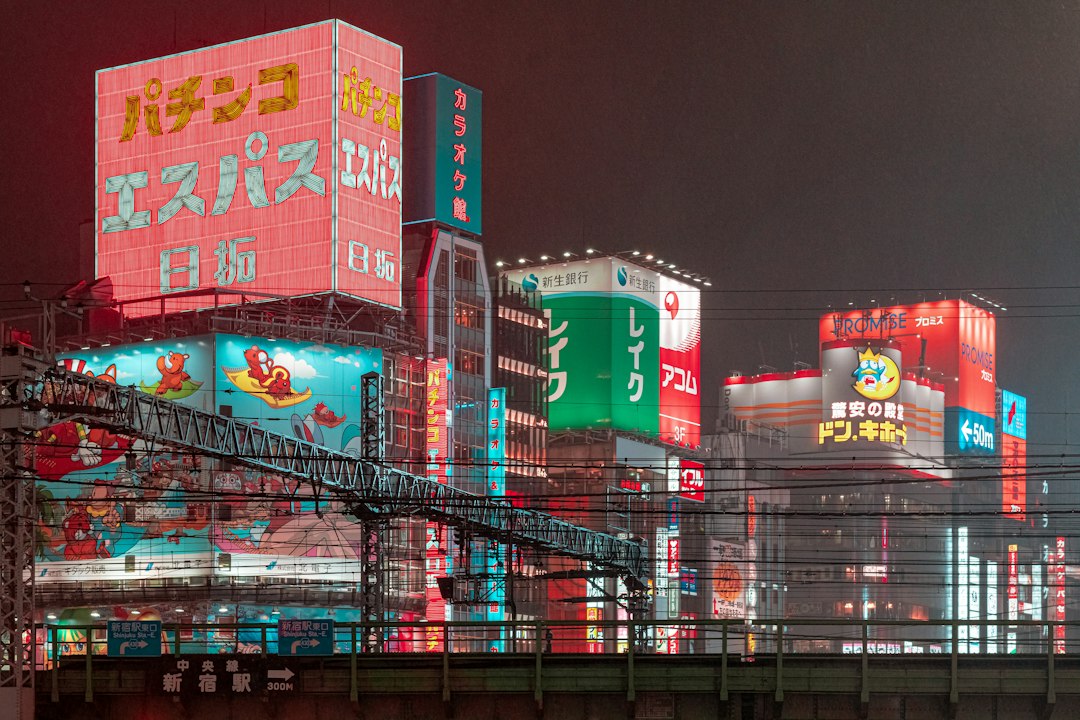 Neon signs for a pachinko parlour, Karaoke Kan and Don Quijote above the railway tracks by Shinjuku Station in Tokyo at night