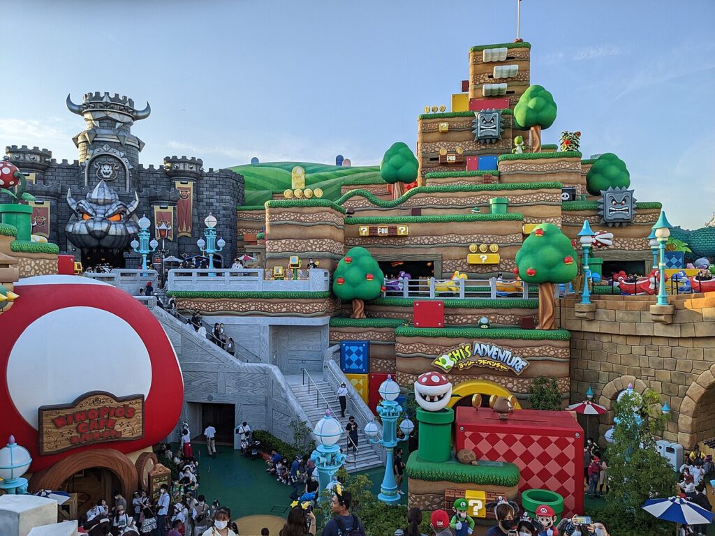 Super Nintendo World at Universal Studios Japan, with Bowser’s Castle above the Yoshi’s Adventure ride, the giant mushroom of Kinopio’s Cafe and visitors in the plaza
