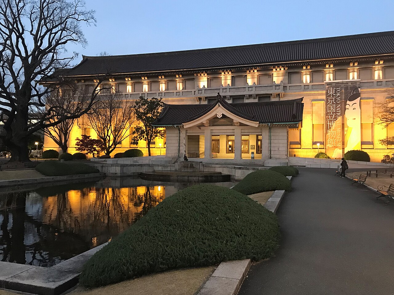 The Honkan, the main building of the Tokyo National Museum in Ueno Park, lit up at dusk behind its ornamental pond
