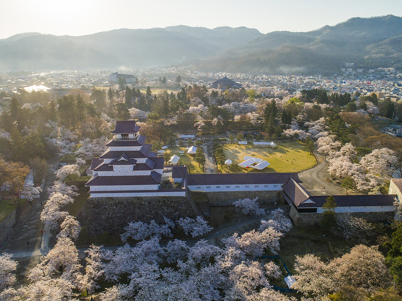 Tsuruga Castle in Aizu-Wakamatsu seen from above, ringed by cherry blossoms with mountains behind