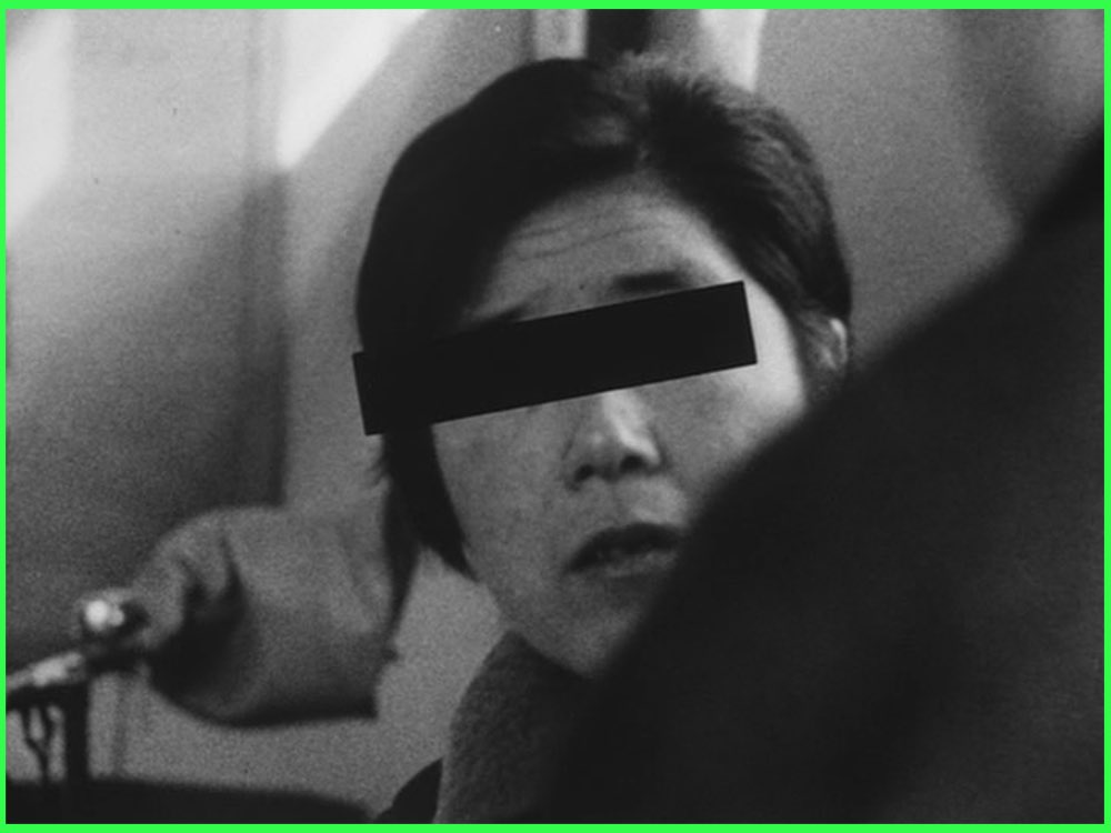 Black and white still from A Man Vanishes (1967): a woman interviewed on camera with a black bar over her eyes