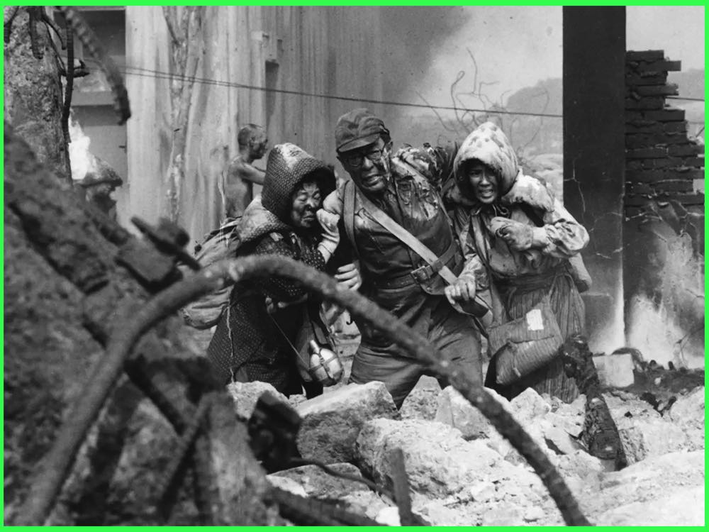 Black and white still from Black Rain (1989): survivors covered in dust stumble through the rubble of bombed Hiroshima