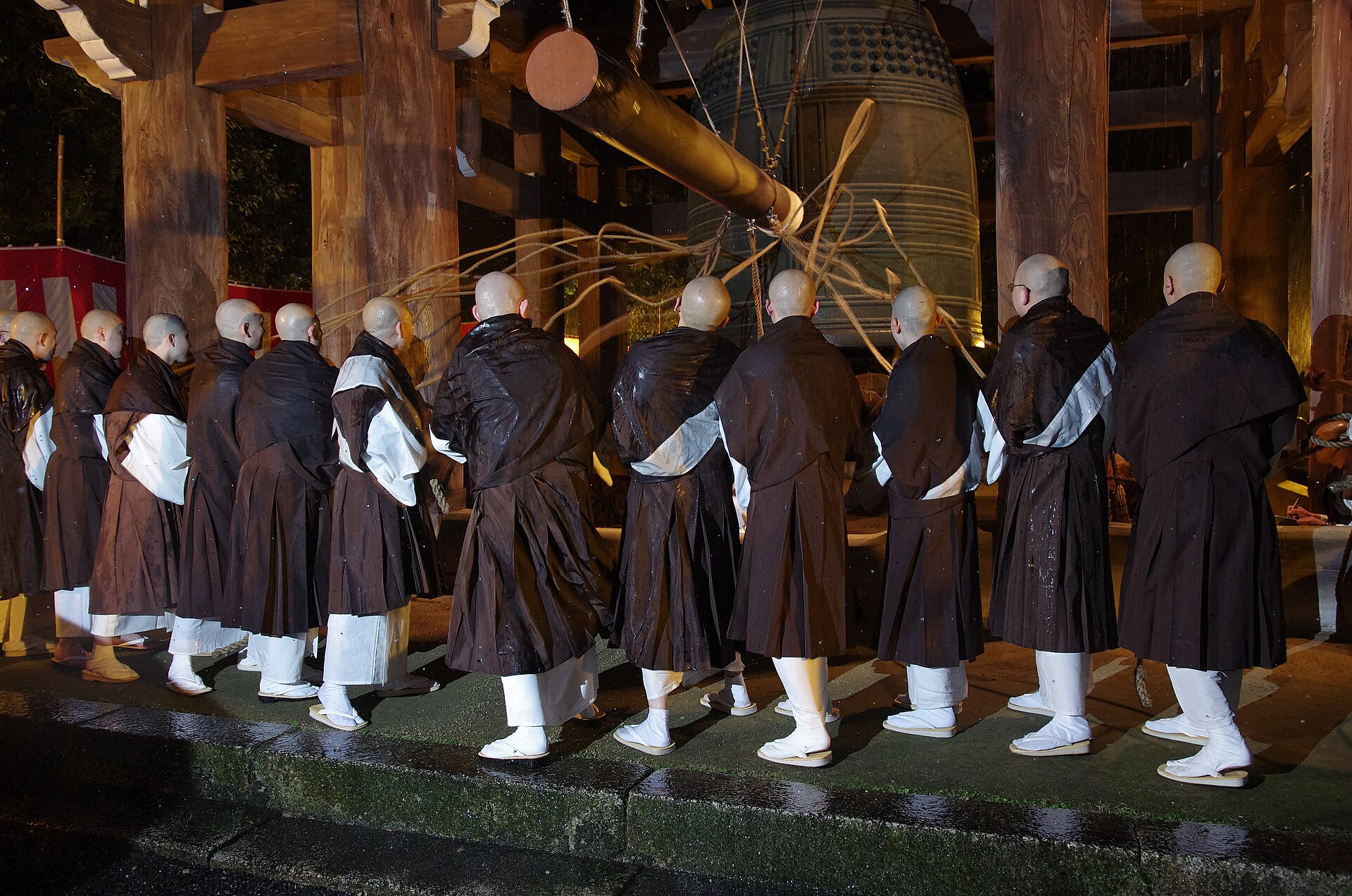 Monks in dark robes hauling on the ropes of the great bell at Chion-in in Kyoto during joya no kane, the New Year’s Eve bell ringing