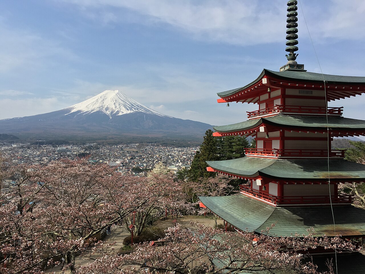 The red Chureito Pagoda in Fujiyoshida with Mount Fuji and cherry blossoms in the background