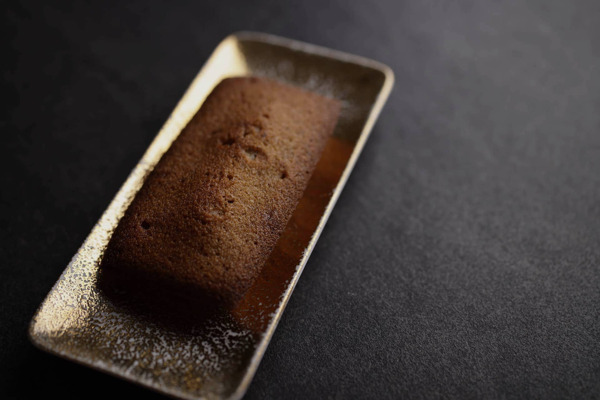 A Dolce Tacubo financier on a long ceramic dish