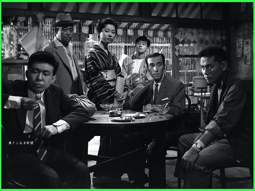 Black and white still from Endless Desire (1958): men in suits and a woman in kimono gathered round a café table