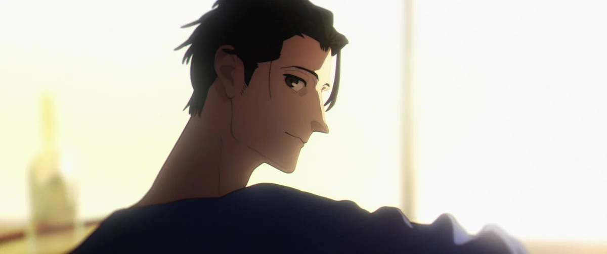 A dark-haired man glances back over his shoulder in front of a bright window, his face half in shadow.