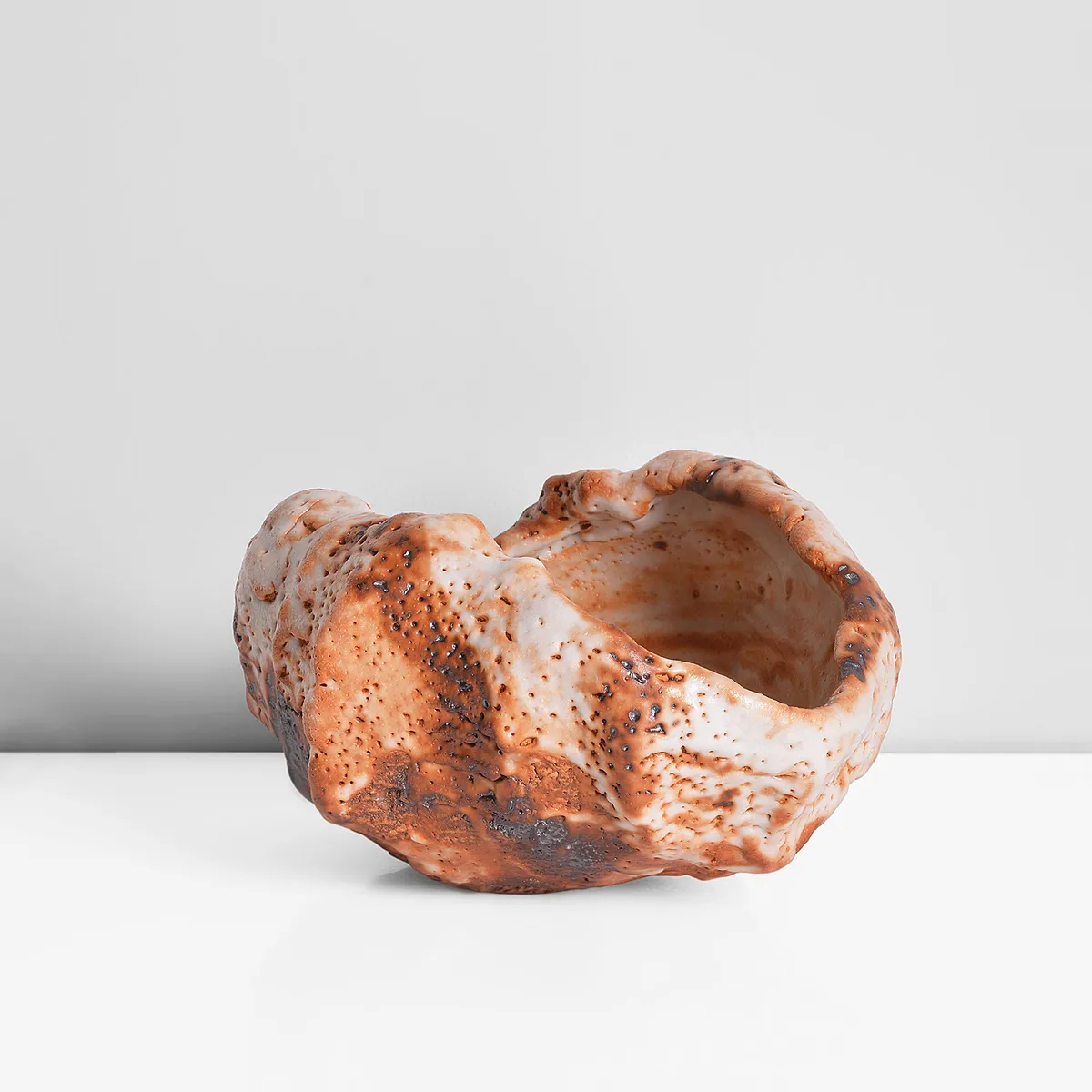 Squeezed and carved tea bowl in thick white shino glaze with rich orange markings