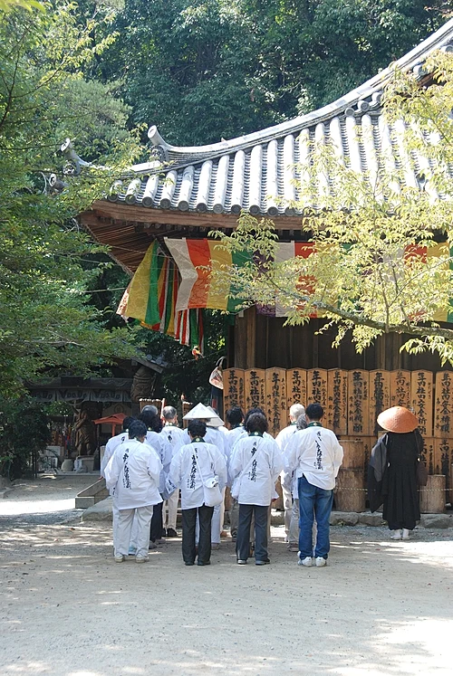 Group of henro pilgrims in white robes reciting the Heart Sutra in front of a hall at Ishite-ji, temple 51 of the Shikoku 88 temple pilgrimage, in Matsuyama