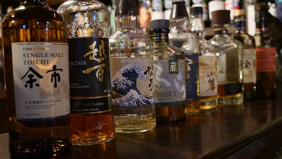 Row of Japanese whisky bottles on a bar counter, including Nikka Yoichi Single Malt