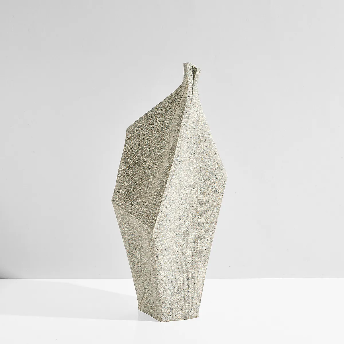 Tall angular pale stoneware sculpture speckled with tiny coloured inlays, on a white surface