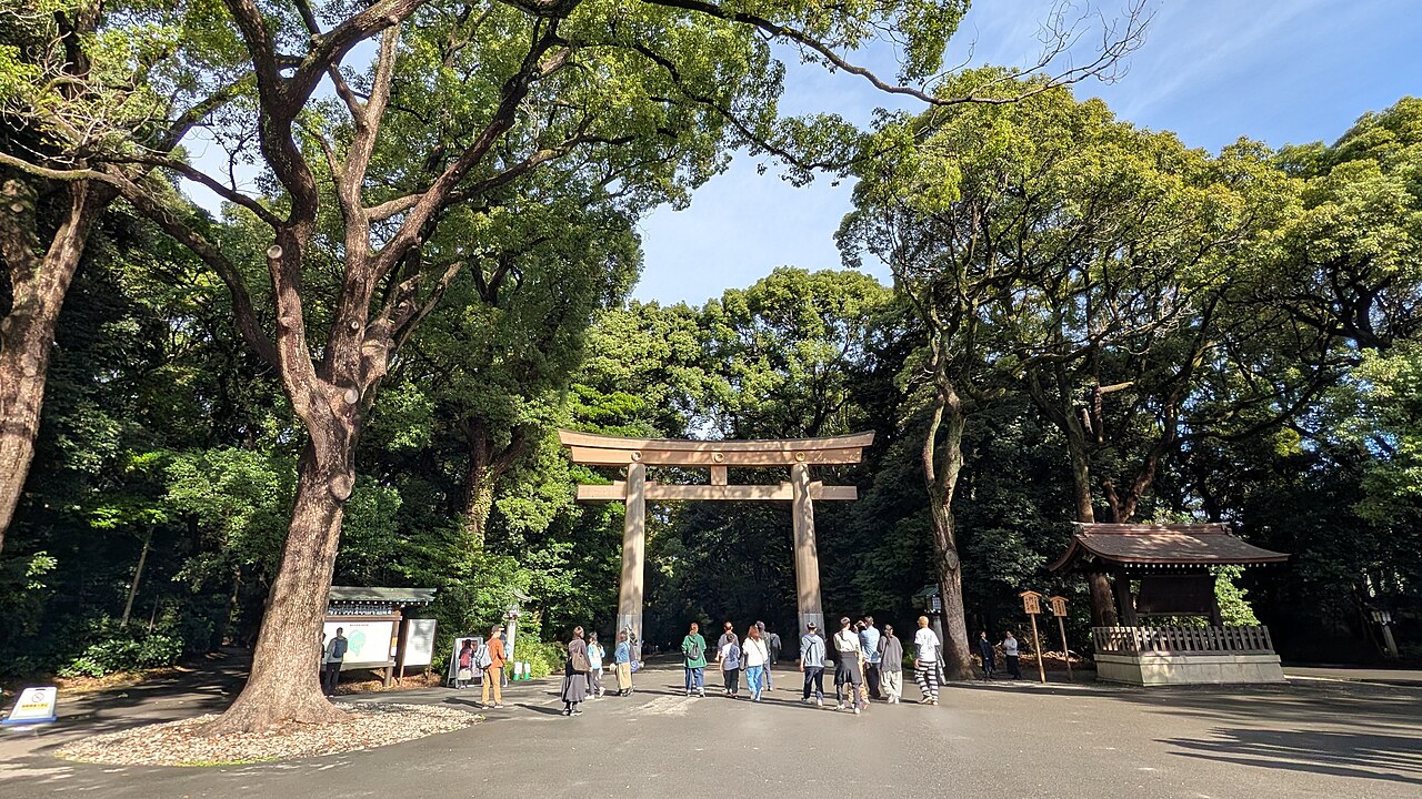 Visitors walking through the large wooden torii gate at the entrance to Meiji Jingu in Tokyo